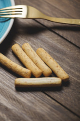 Sticks of bread next to a fork and a plate.