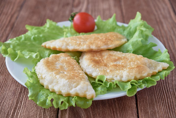Cheburek pie with meat on a wooden background
