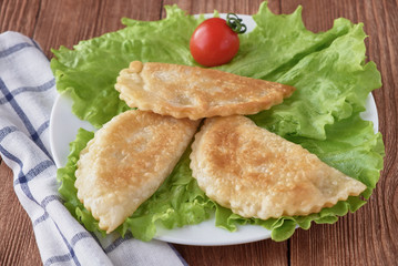 Cheburek pie with meat on a wooden background