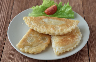Cheburek pie with meat on a wooden background