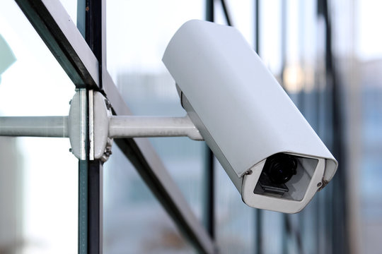 white security cctv camera on glass facade