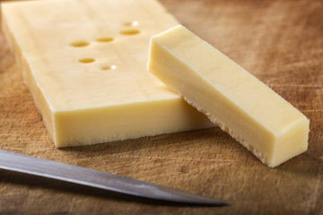 Emmental cheese with knife on wood