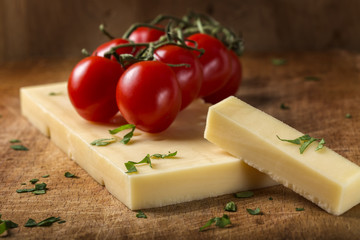 Emmental cheese with cherry tomatoes and herbs on wood