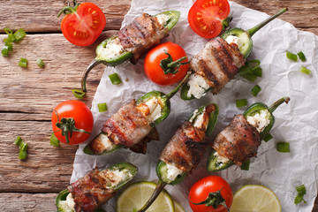 Roasted jalapeno peppers stuffed with cheese wrapped in bacon close-up. Horizontal top view
