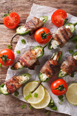 Roasted jalapeno peppers stuffed with cheese wrapped in bacon close-up. vertical top view