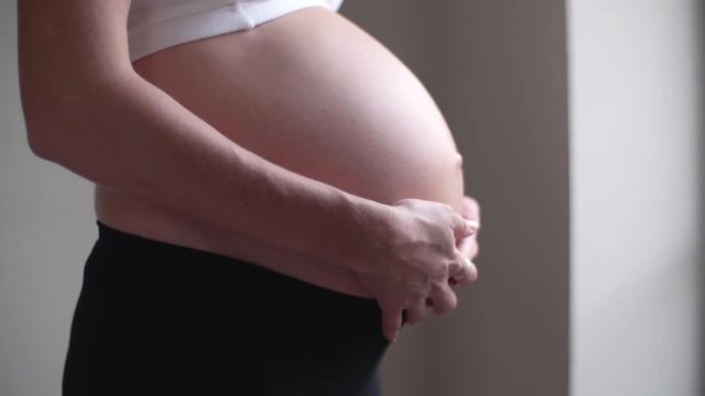 Close-up of pregnant woman rubbing her bare stomach