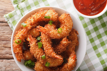 Fried shrimp in coconut breading and the sauce in a bowl close-up. Horizontal top view