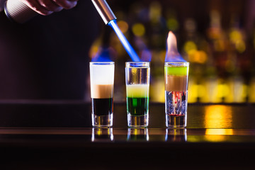 Three multi-layer burning cocktail. The bartender ignites them lighter.