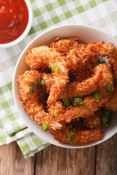Fried shrimp in coconut breading and the sauce in a bowl close-up. Vertical top view