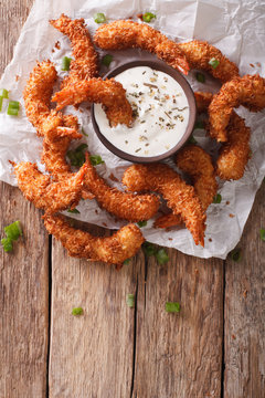 prawns fried in coconut close-up and cream sauce on parchment. vertical top view