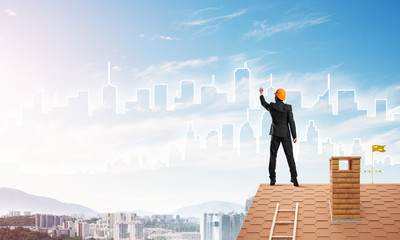 Man architect draw silhouette of modern city on blue sky. Mixed media