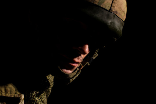 Portrait of soldier with half face in deep shadow.