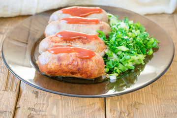 Homemade sausages on a plate with greens on a rustic table.