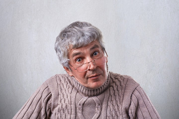 Senior, elderly man in glasses looking with wide open eyes having clever expression. A wise grandfather in glasses having surprised expression isolated over white background. People and emotions.