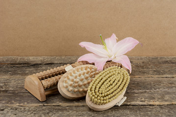 Beautiful composition with pink lily and massage brushes on wooden background, skin and body care concept