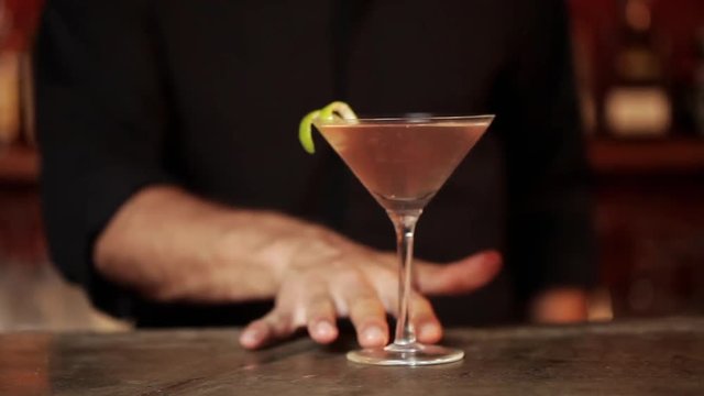 Bartender adding lime rind garnish to cosmopolitan