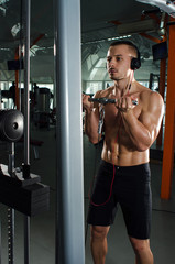 the young man shakes his muscles in the gym