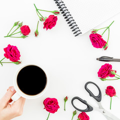 Frame with flowers, notebook, pen and scissors on white background. Girl hands and coffee mug. Flat lay, top view