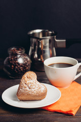 a white cup with a drink and a cupcake on a plate, a ladle and a jar with coffee beans