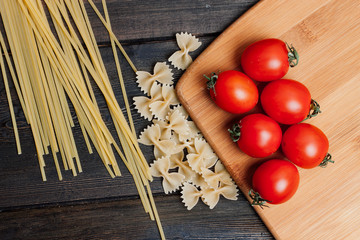 red tomatoes lie on a board and spaghetti with noodles on a table