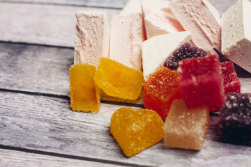 Multicolored marmalade and white marshmallow on a wooden background
