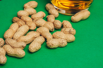 peanuts in shell on a green background and a mug with a drink