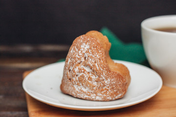 cupcake in a plate, powdered sugar and a napkin in the background