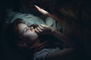 woman looking in the phone lying on the bed