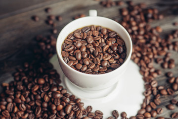 Coffee beans in a cup and on a table