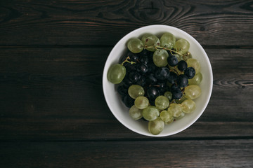 Dark and light grapes in a plate, top view