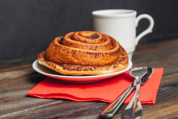 a cinnamon roll and a white mug in the background