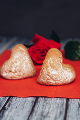 Fototapeta na wymiar cookies in the form of hearts on a red napkin, flower and glasses on a table