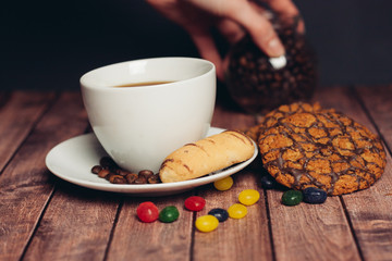 cup with a drink and cookies in a saucer, multi-colored sweets