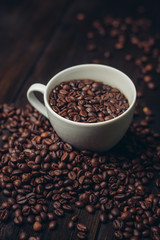 Coffee beans in a white mug and on a wooden table