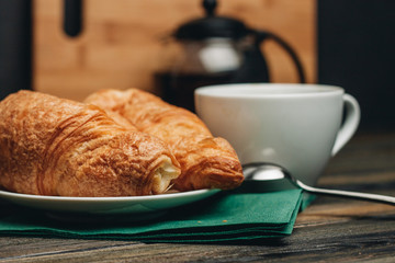 croissants in a saucer, green napkin and a white mug