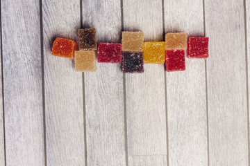Multicolored marmalade cubes on a wooden background