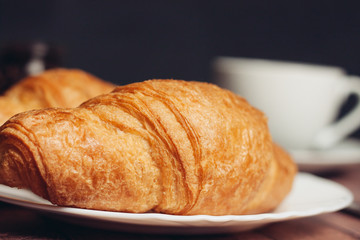 croissant on a saucer and a cup of coffee