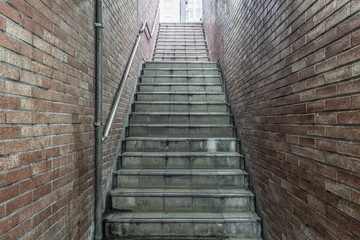 Old underground concrete stair with brown brick wall