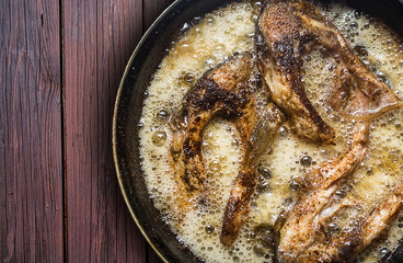 Fish in a frying pan. horizontal view from above. On the wood