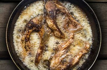 Fish in a frying pan. horizontal view from above. On the wood