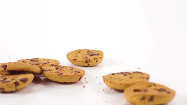 Chocolate chip cookies tumble in slow motion onto a white cyc