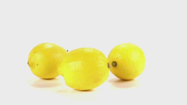 Slow mo shot of three lemons falling in slow motion onto a white cyc