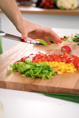 Close up of  woman's hands cooking in the kitchen. Housewife slicing ​​fresh salad. Vegetarian and healthily cooking concept
