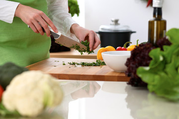 Closeup of human hands cooking vegetables salad in kitchen on the glassr table with reflection. Healthy meal and vegetarian concept