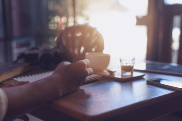 Casual Business man writing book with a phone and a camera on the coffee table.