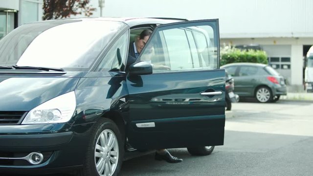 Businessman getting out of car talking on cell phone