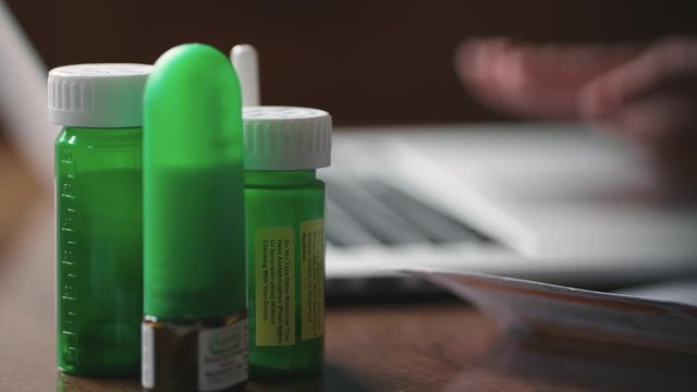 Prescription drugs and typing on a laptop close up