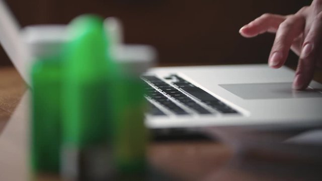 Prescription drugs and typing on a laptop close up