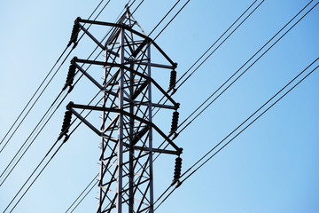 High-voltage tower and electric lines over blue sky