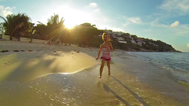 Child running along the surf at sunset. Slow motion